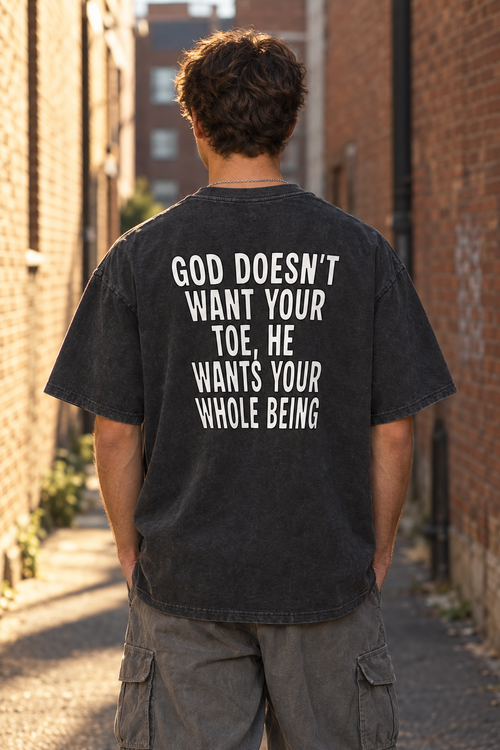 Model wearing the UNQLFD washed black vintage tee with He Wants Your Whole Being back print