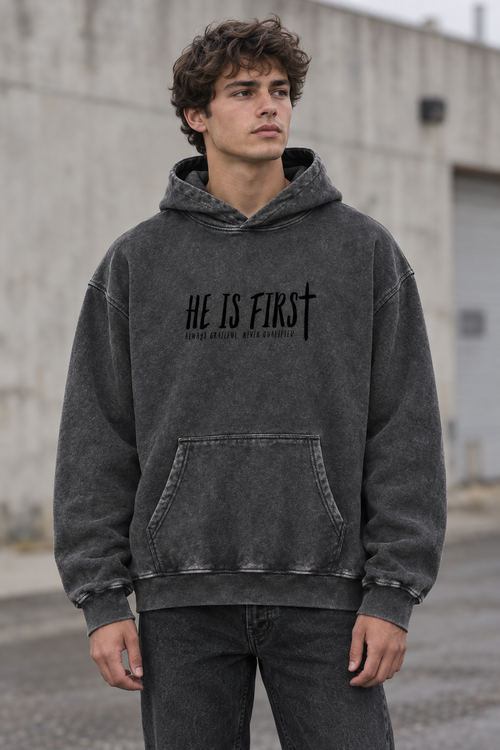Model wearing the UNQLFD He Is First vintage wash hoodie in washed charcoal