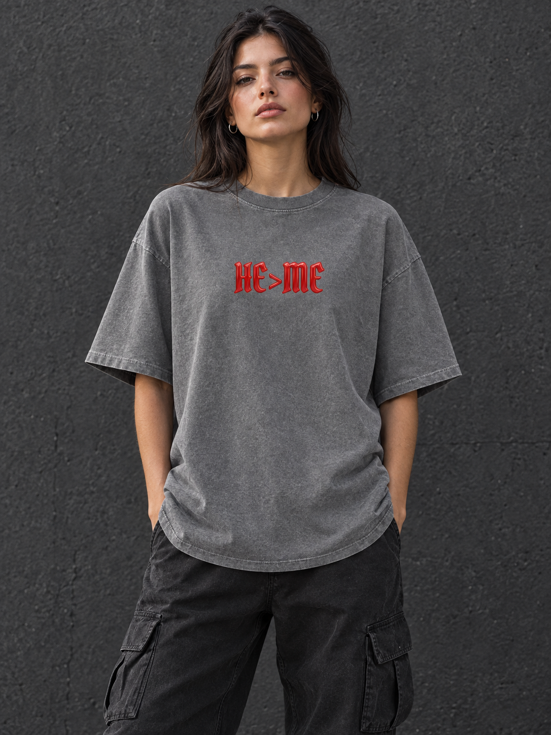 Model wearing HE IS GREATER THAN ME Vintage Wash Cotton Tee, showing the red HE>ME chest graphic and full-length hem.